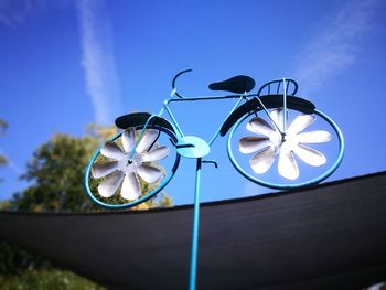 Low angle view of bicycle windspiel against blue sky