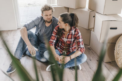 Couple sitting on floor next to moving boxes