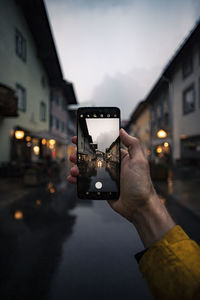 Man photographing illuminated smart phone in city