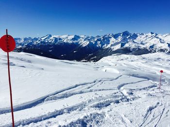 Scenic view of snowcapped mountains against blue sky on sunny day