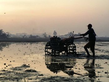 Reflection of people in water at sunset