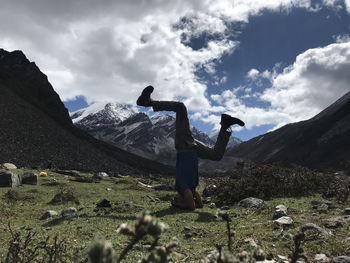 Man doing handstand on field against mountains