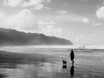 Rear view of woman walking with dog at beach