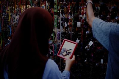 Rear view of woman photographing mobile phone