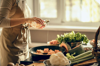 Hands of young woman put pumpkin on frying pan for baking in kitchen. the concept of healthy eating