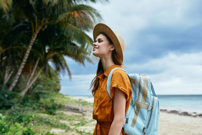 Young woman looking away while standing on land against sky