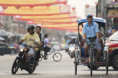 People riding vehicles on road in city