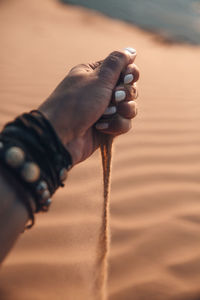 Midsection of woman holding sand on beach