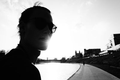 Portrait of young man wearing sunglasses against sky in city