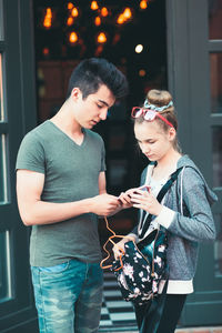 Smiling teenage friends using mobile phone in city