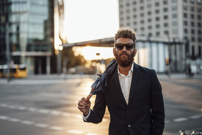 Businessman wearing sunglasses carrying umbrella on shoulder