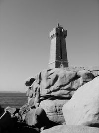 Lighthouse by sea against clear sky