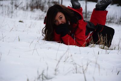 Portrait of young woman lying on snow covered land