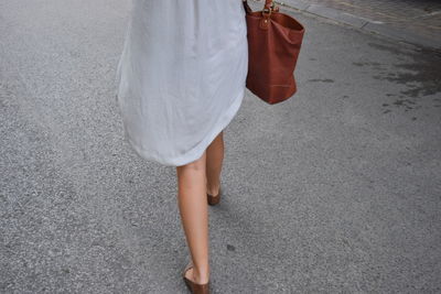 Low section of woman walking on city street