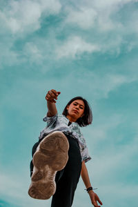 Low angle view of woman holding umbrella against sky