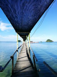 Bridge over sea against blue sky