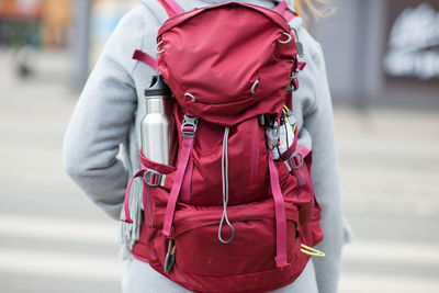 Rear view of woman carrying maroon backpack in city