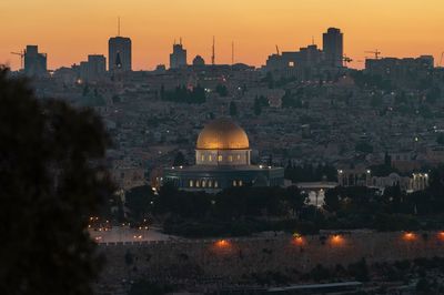 Illuminated buildings in city at sunset