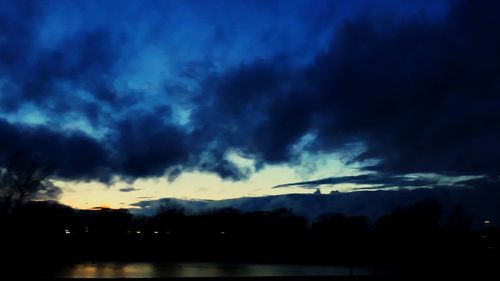 Silhouette of trees against cloudy sky