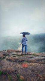 A young man with umbrella enjoying the beauty of season and nature