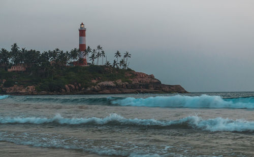 Lighthouse by sea against clear sky