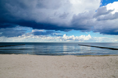 View of calm beach against cloudy sky