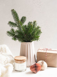 Christmas tree branches in modern ceramic vase, gift wrapped and cozy home decor. 
