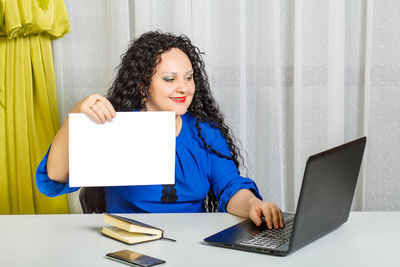 Young woman using phone while sitting on table