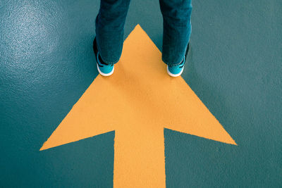 Low section of man standing on arrow sign