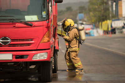 Firefighter standing by fire engine on street