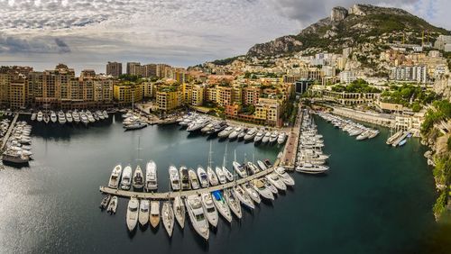 High angle view of sailboats moored in sea against buildings in city