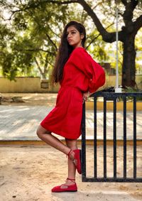 Beautiful young woman standing by railing in park