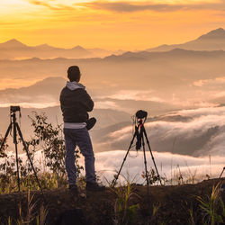 Man photographing against sky during sunset