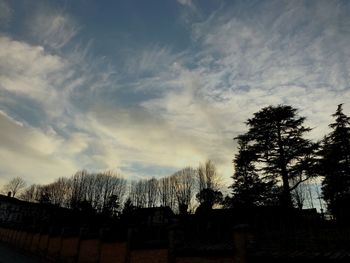 Low angle view of silhouette trees and buildings against sky