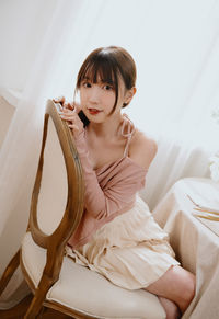 Young woman sitting on bed at home