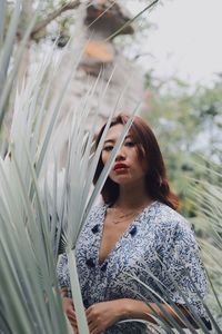 Woman looking away while standing against plants