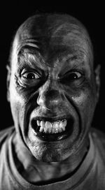 Close-up portrait of angry man against black background