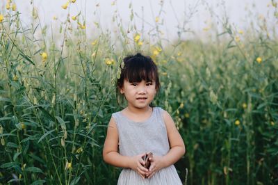 Portrait of girl standing by flowering plants