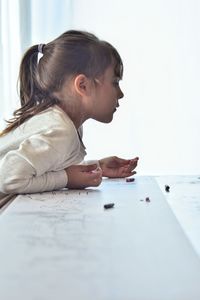 Side view of girl playing at table