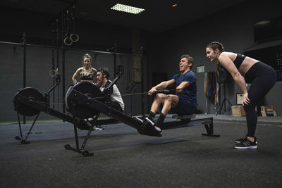 Athletes exercising with rowing machine at gym