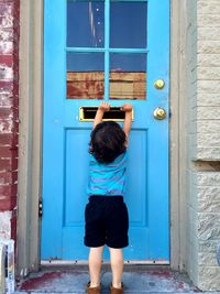 Rear view of boy holding door