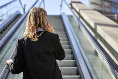 Rear view of young woman standing on escalator