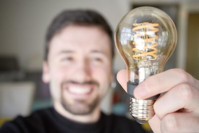 Close-up of man holding light bulb