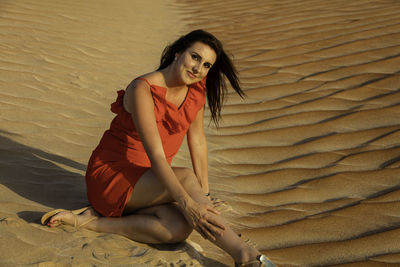 Portrait of woman sitting on sand dune at desert