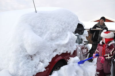 Family cleaning snow on car