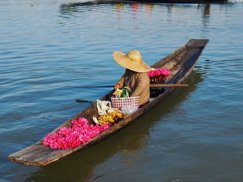 Woman with pink flowers in boat on lake