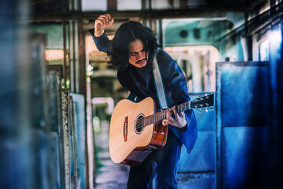 Young guitarist playing guitar in bus