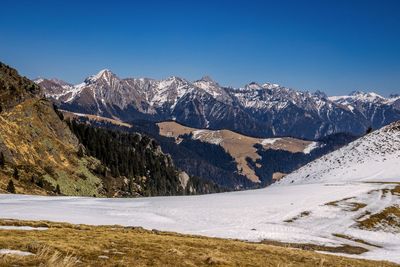 Scenic view of snowcapped mountains against clear blue sky