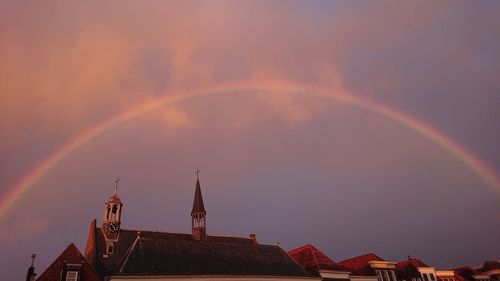 Low angle view of rainbow over building against sky