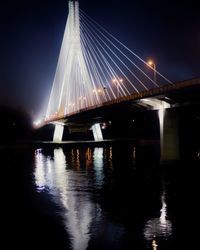 Bridge over river against sky at night